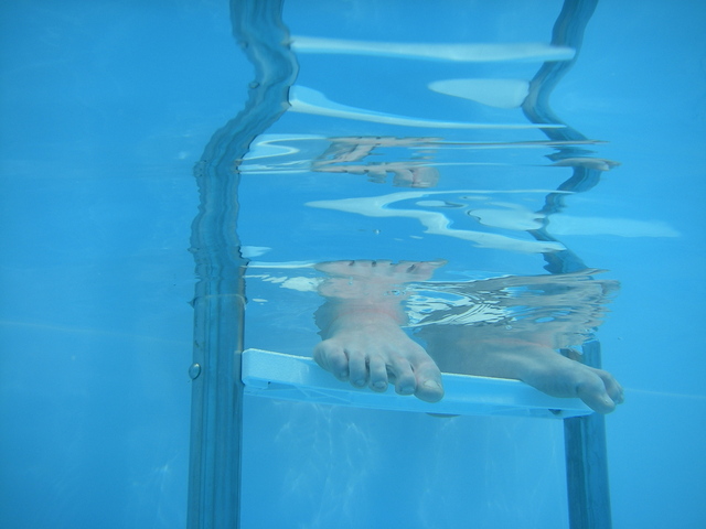 nohy člověka v čisté bazénové vodě